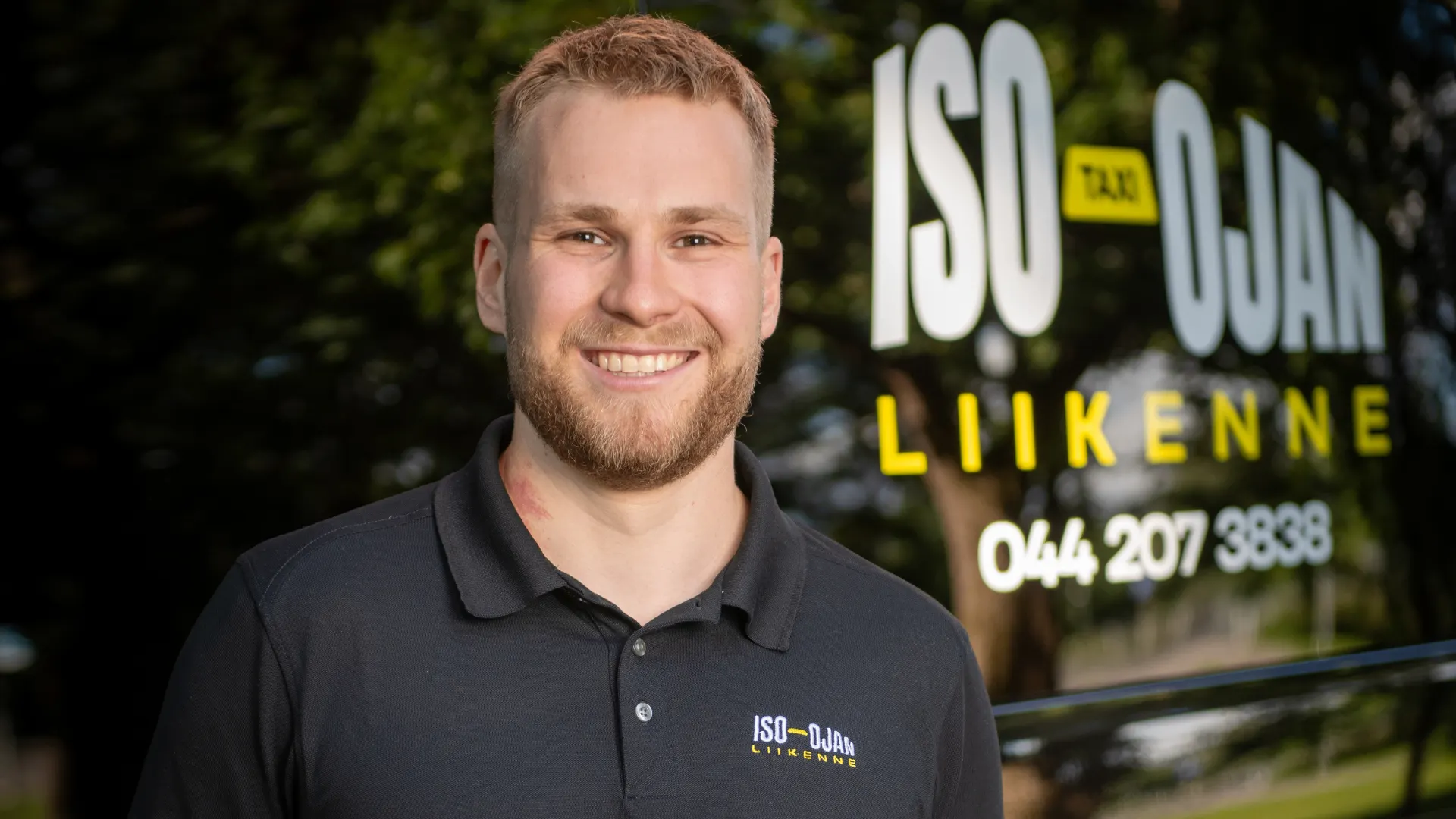 Iso-Ojan Liikenteen kuljettaja hymyilee taksin ratissa